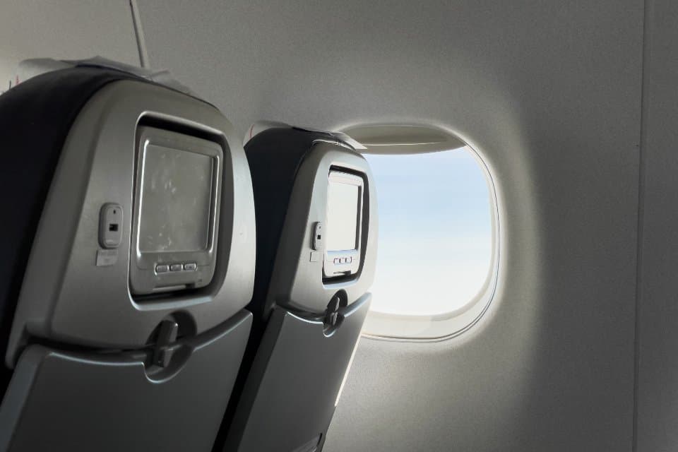 Seatback screens beside an aircraft cabin window