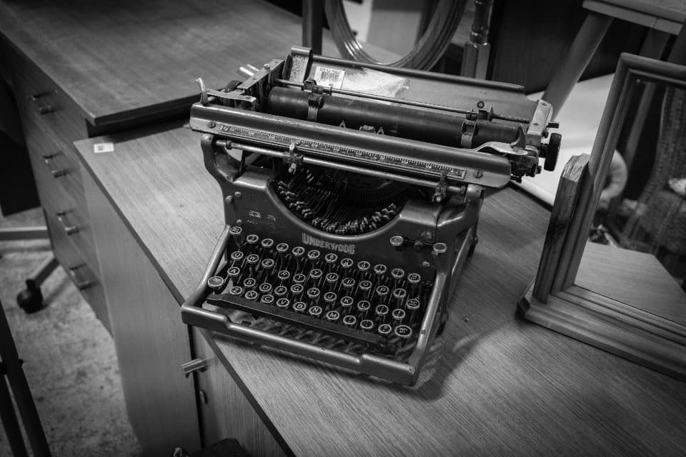 A vintage Underwood typewriter on a wooden desk, in black and white